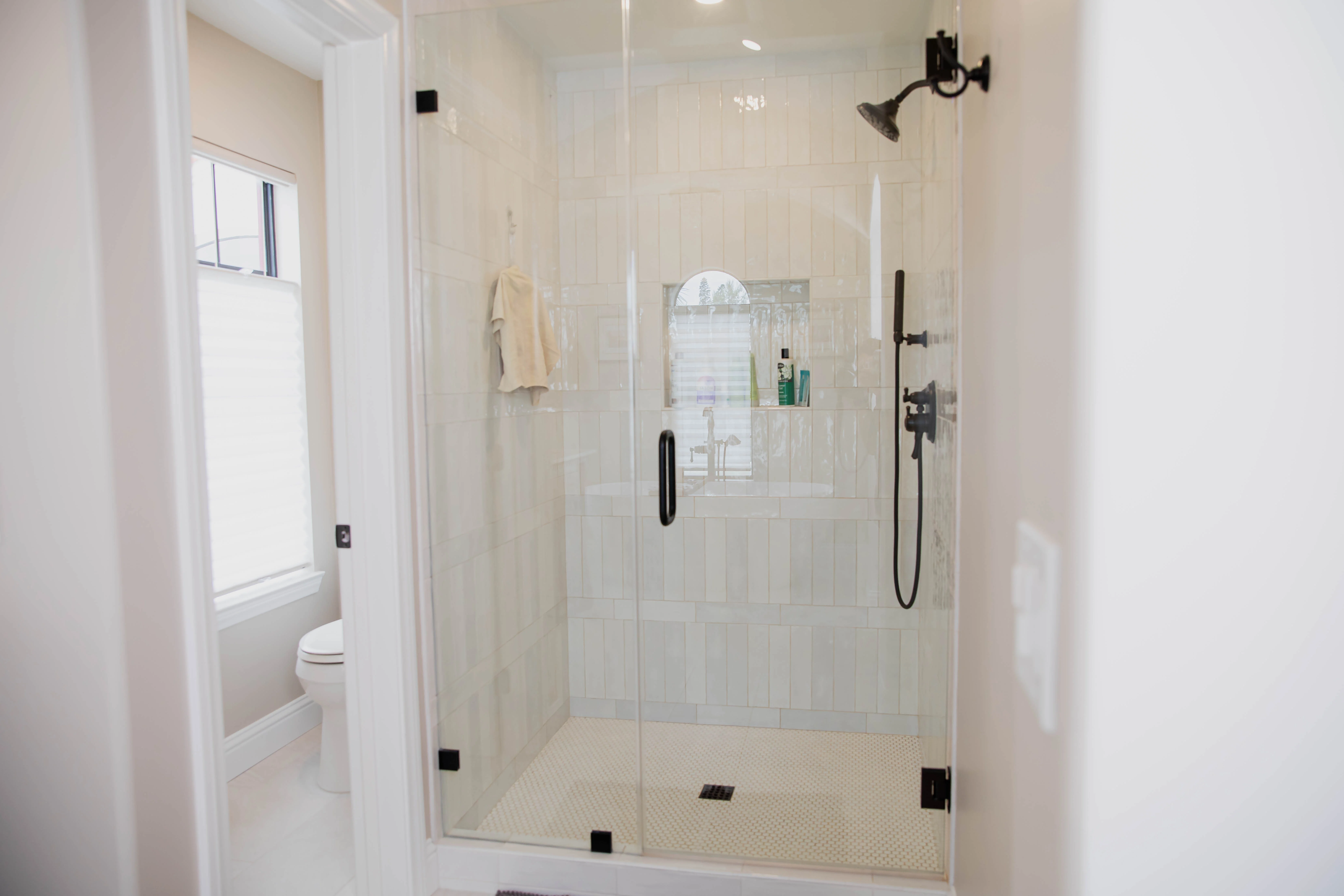 Modern bathroom shower with white subway tile, frameless glass doors, and black fixtures