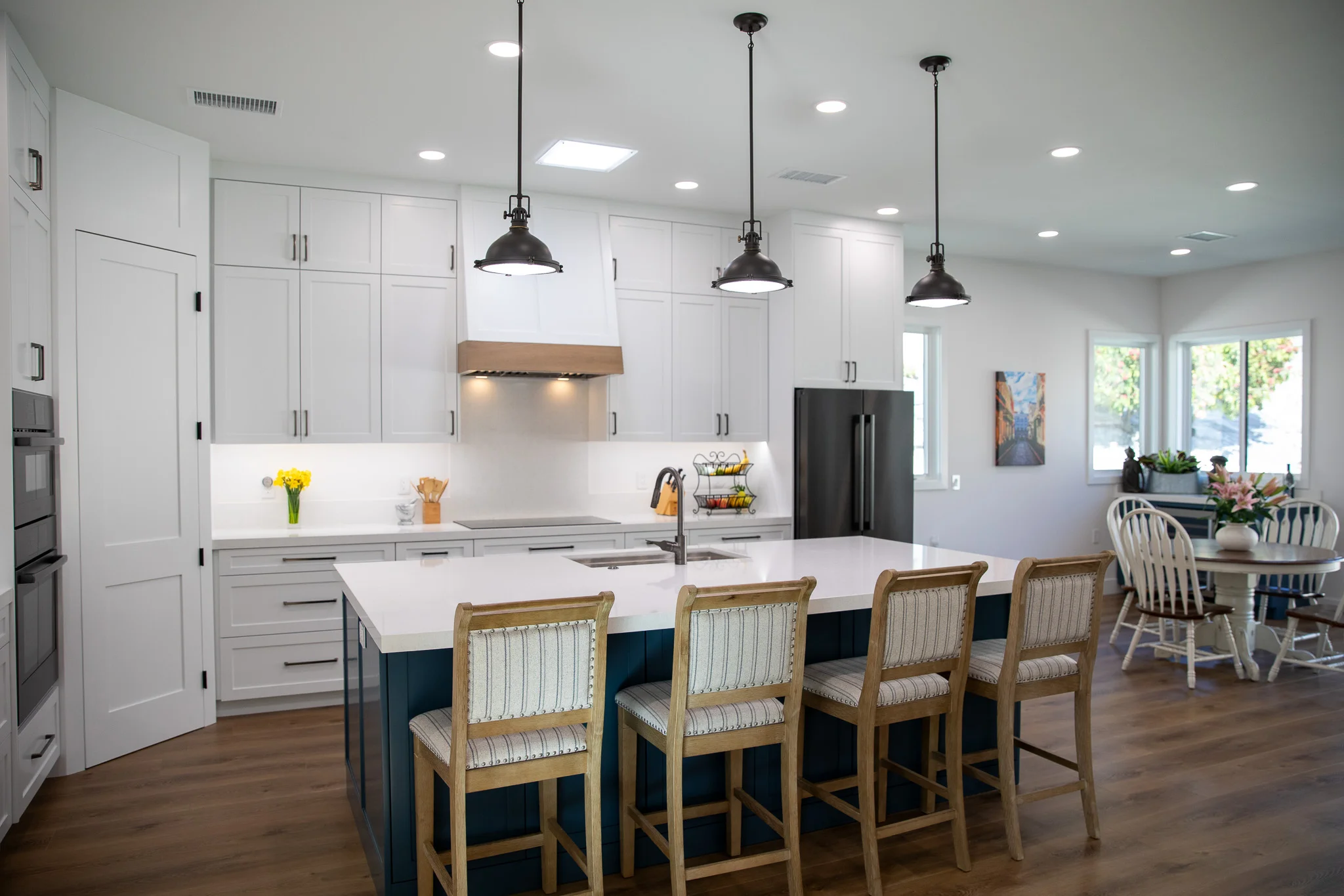 Modern kitchen with white cabinets, navy island, and black pendant lights
