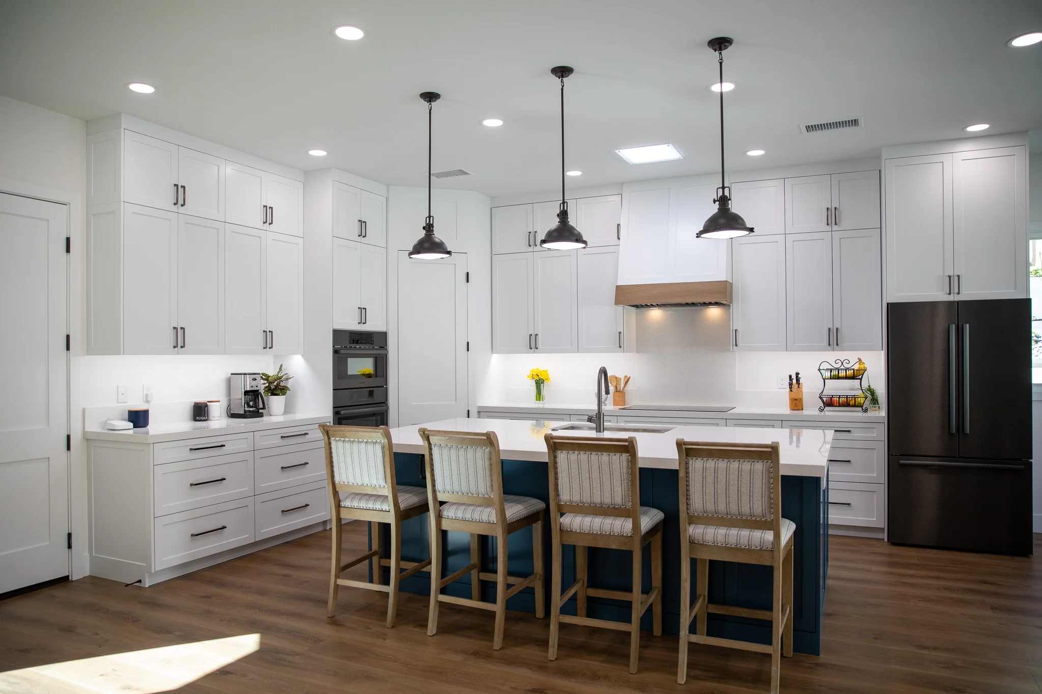 Modern kitchen with white cabinets, navy island, and black pendant lights