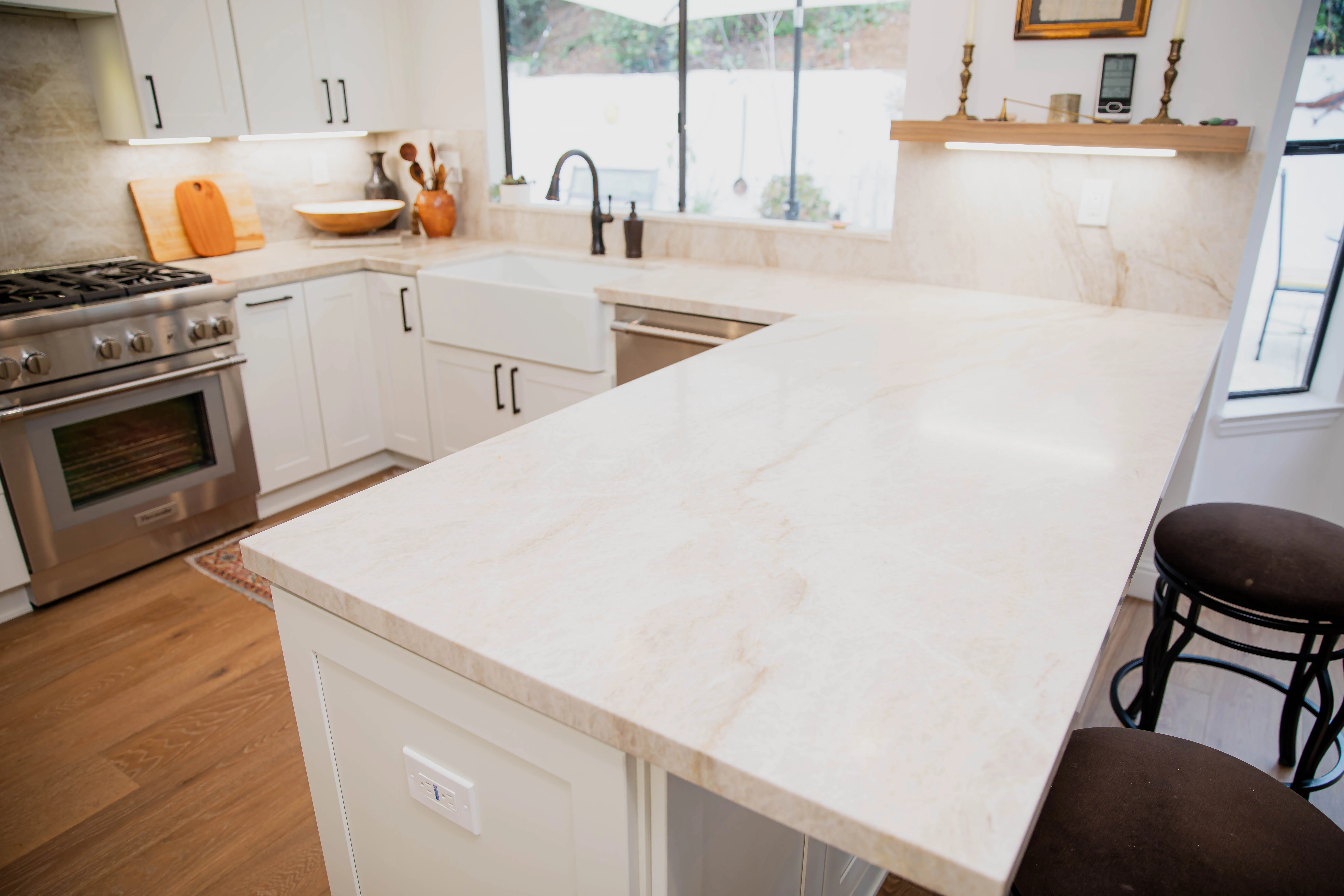 Newly installed stone countertop on white kitchen cabinets in a San Diego home, showing a clean sink cutout and finished edge along the backsplash. The surface runs the full length of the kitchen wall with no visible seam gaps at the corners.
