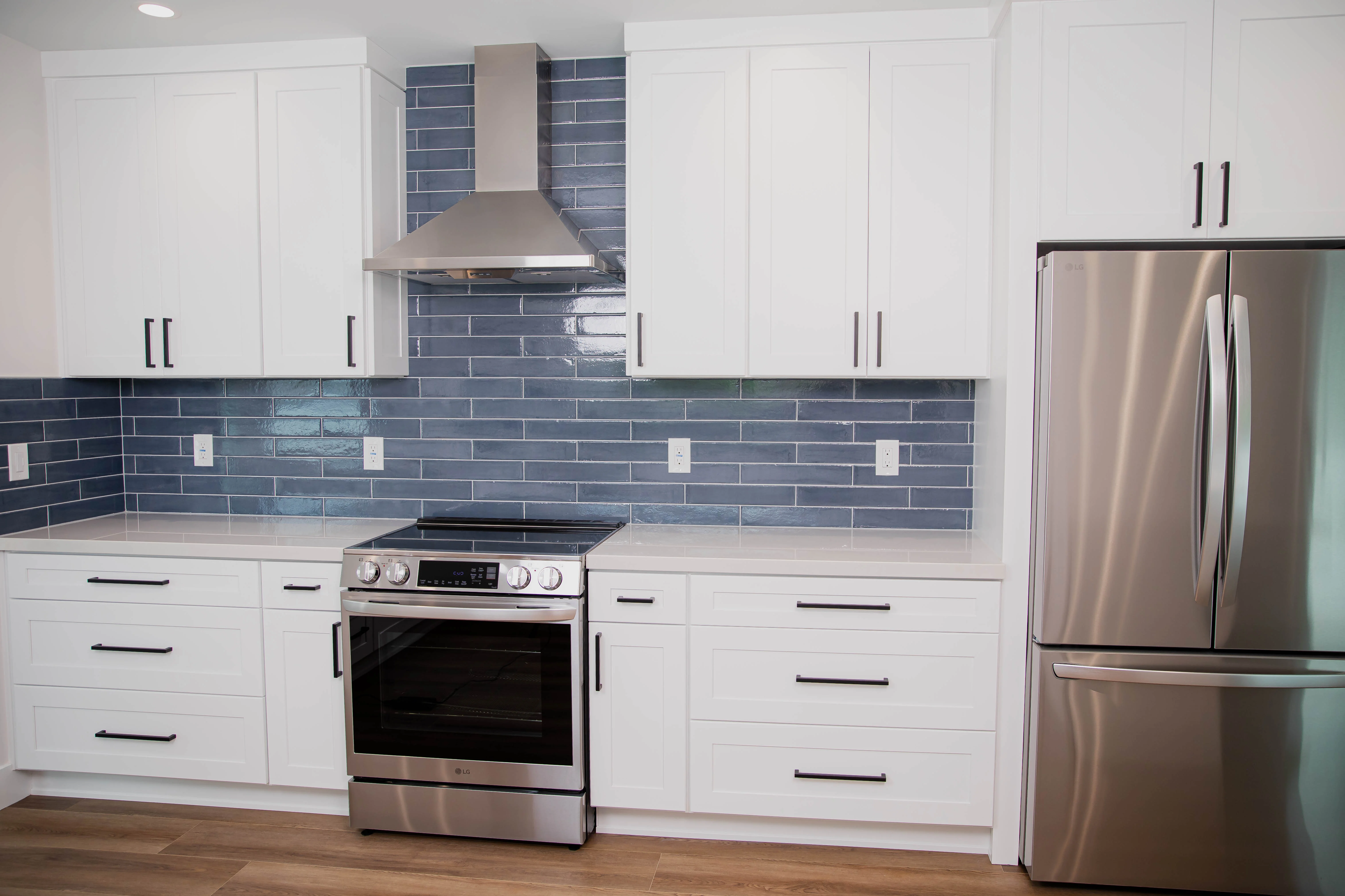 Freshly installed kitchen tile backsplash in a San Diego home, showing clean grout lines, precise cuts around electrical outlets, and a smooth transition between the countertop and upper cabinets. The tile runs the full width of the cooking area, with even spacing and a sealed finish throughout.